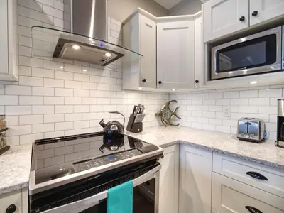 a kitchen with white cabinets and a stove top oven at Oceanfront Relaxing & Stunning View - Pet Friendly in Port Renfrew
