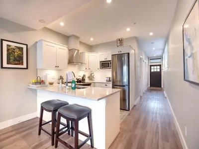a kitchen with white cabinets and a counter with stools at Oceanfront Relaxing & Stunning View - Pet Friendly in Port Renfrew