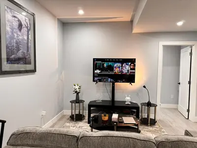 a living room with a couch and a flat screen tv at Private 1BR Basement Suite in NE Calgary in Calgary