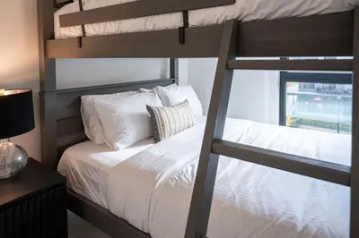 a bedroom with a bunk bed with white sheets and pillows at The Ridge - 3 Bedroom Condo - Roof Top Hot Tub in Revelstoke