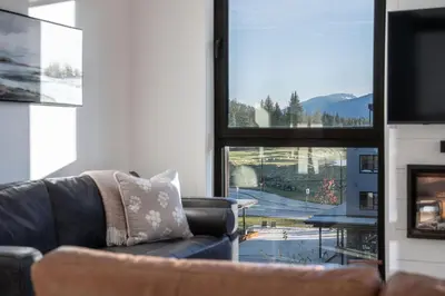 a living room with a couch and a large window at The Ridge - 3 Bedroom Condo - Roof Top Hot Tub in Revelstoke
