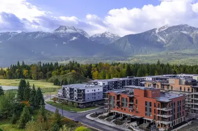 an apartment complex with mountains in the background at The Ridge - 3 Bedroom Condo - Roof Top Hot Tub in Revelstoke