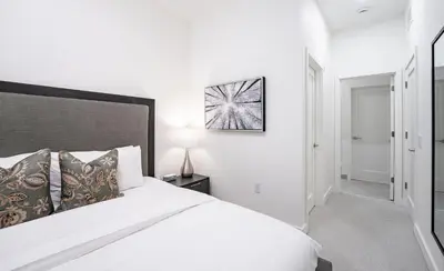 a white bedroom with a large bed and a lamp at The Ridge - 3 Bedroom Condo - Roof Top Hot Tub in Revelstoke
