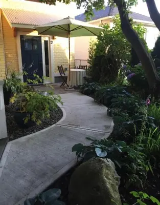 a patio with an umbrella and some plants and a house at Beautiful Oasis in prime Vancouver BC with 2 bed and patio PLUS Studio available in Vancouver