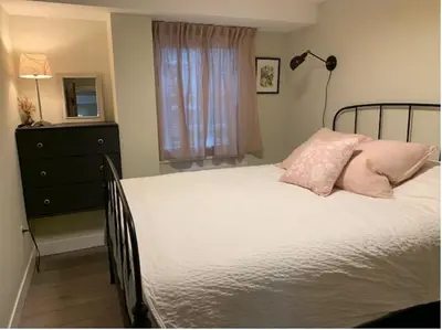 a bedroom with a bed with pink pillows and a lamp at Beautiful Oasis in prime Vancouver BC with 2 bed and patio PLUS Studio available in Vancouver