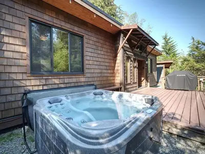a hot tub on a deck next to a house at A slice of paradise with Hot Tub - Pet Friendly in Port Renfrew
