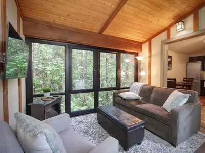 a living room with a couch and a large window at Private treed setting - no pets - garden view in Port Renfrew