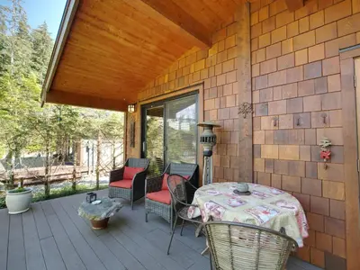 a patio with a table and chairs on a deck at Quiet Romantic Getaway - Non Pet Friendly in Port Renfrew