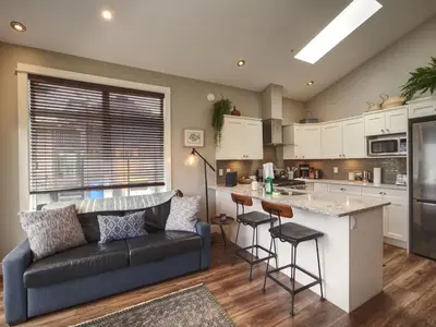 a living room with a couch and a kitchen at Oceanfront Marina & Mountain views- pet friendly in Port Renfrew