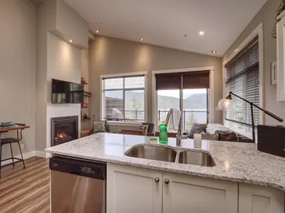 a kitchen with a sink and a fireplace at Oceanfront Marina & Mountain views- pet friendly in Port Renfrew