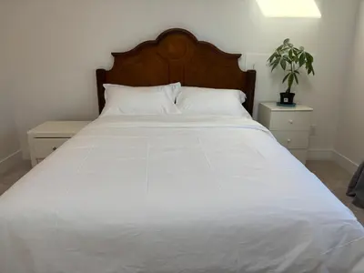 a white bed with a wooden headboard and white sheets at Comfortable Private Room in a Shared Home in Richmond