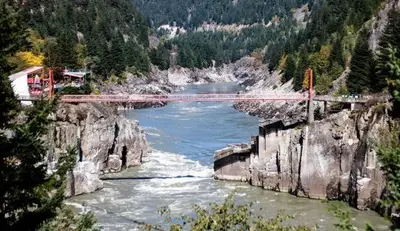 a river with a bridge in the middle of a mountain at Lotus Hideaway in Boston Bar