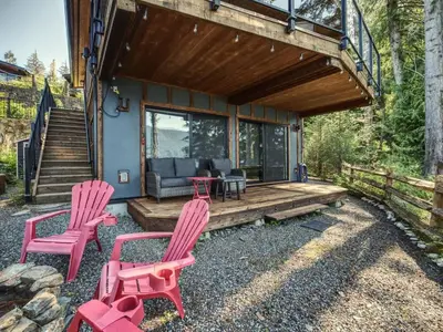 a house with two red chairs and a porch at Oceanfront view 2 entertainment areas -Pet Friendly in Port Renfrew
