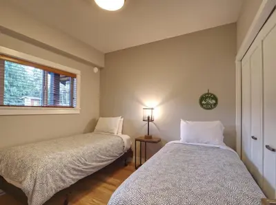 two beds in a room with a window at The Salty Dog - Oceanfront Getaway - Great View - Pet Friendly in Port Renfrew