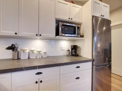 a kitchen with white cabinets and a stainless steel refrigerator at The Salty Dog - Oceanfront Getaway - Great View - Pet Friendly in Port Renfrew
