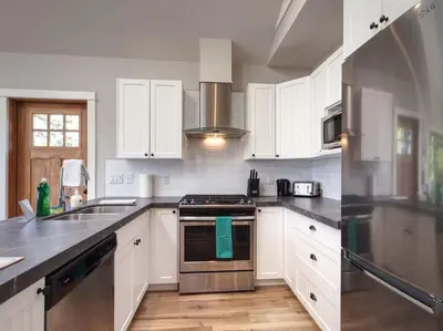 a kitchen with white cabinets and stainless steel appliances at Oceanfront & Amazing Views - Pet Friendly - 2bdrm in Port Renfrew