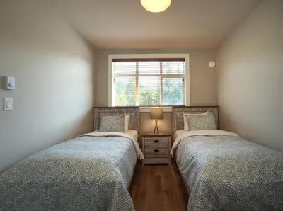 two twin beds in a room with a window at Oceanfront & Amazing Views - Pet Friendly - 2bdrm in Port Renfrew