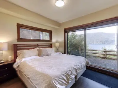 a bedroom with a large bed and a large window at Hera's Cove - Oceanfront Oasis - Pet Friendly in Port Renfrew
