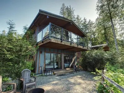 a house in the woods with a balcony at Hera's Cove - Oceanfront Oasis - Pet Friendly in Port Renfrew