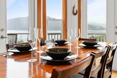 a wooden table with wine glasses and a dining room at Hot tub - Sauna - Panoramic Ocean View THE POINT - Pet Friendly in Port Renfrew