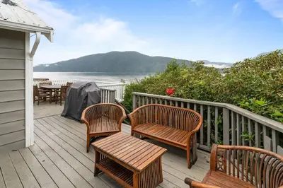 a deck with three chairs and a table with a view of the water at Hot tub - Sauna - Panoramic Ocean View THE POINT - Pet Friendly in Port Renfrew