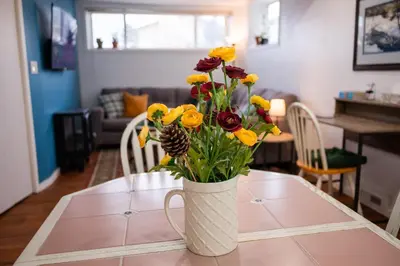 a vase filled with yellow and red flowers on a table at Spacious 2-Bedroom Basement Suite in Whitehorn, Close to Calgary Airport, Hospital, & Train in Calgary