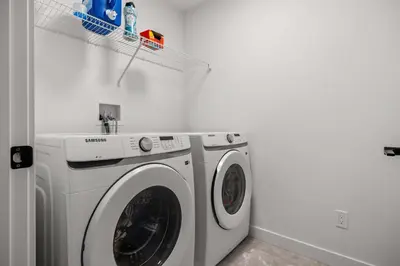 a white washing machine in a white laundry room at NEW Family 3BR Upper Suite w Kid's Play Den, Free Banff Pass in Calgary