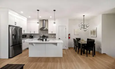 a kitchen with white cabinets and a table with chairs at Large 5BR Family Home w Kids Play Den & Private Basement Suite Included, FREE Banff Pass! in Calgary