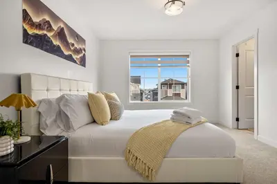 a bedroom with a white bed and a window at Large 5BR Family Home w Kids Play Den & Private Basement Suite Included, FREE Banff Pass! in Calgary