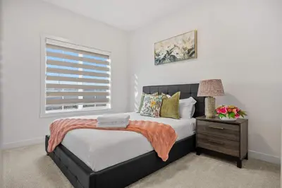 a bedroom with a bed and a nightstand and a window at Large 5BR Family Home w Kids Play Den & Private Basement Suite Included, FREE Banff Pass! in Calgary