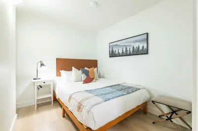 a white bedroom with a bed and a chair at Wintergreen 26 by Outpost Whistler in Whistler