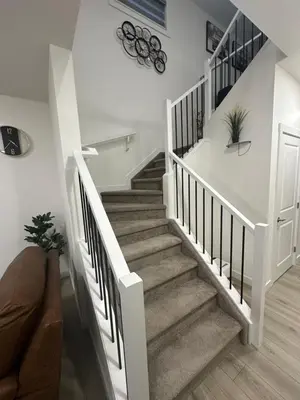 a staircase in a home with white walls and wooden floors at Brand New 3 Bedroom house SW Edmonton in Edmonton
