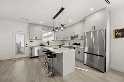 a kitchen with white cabinets and a stainless steel refrigerator at Bright Modern 3 Bedroom Suite in Vancouver in Vancouver