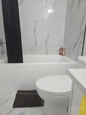 a white bathroom with a toilet and a bath tub at Cy Becker Drive 2023 Luxury Home in Edmonton