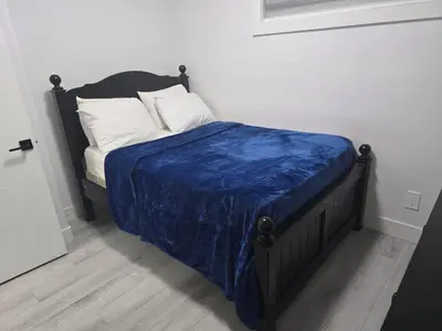 a bed with a blue comforter and white pillows at Cy Becker Drive 2023 Luxury Home in Edmonton