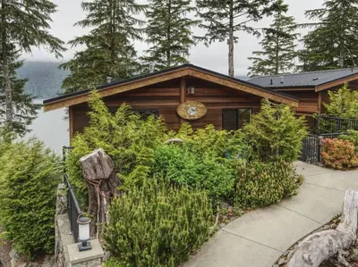 a log cabin with a clock on the front of it at Going Coastal ABC - Oceanfront - Pet Friendly in Port Renfrew