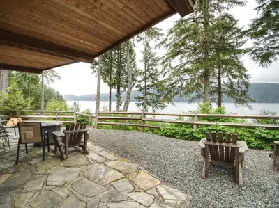 a patio with chairs and a table with a view of the water at Going Coastal AB - Oceanfront - Pet Friendly in Port Renfrew