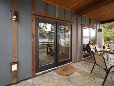 a screened porch with glass doors and a table and chairs at Going Coastal AB - Oceanfront - Pet Friendly in Port Renfrew