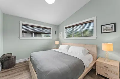 a bedroom with a large bed and two windows at Spacious Oceanview - 2 living rooms & fridges - Pet Friendly in Port Renfrew