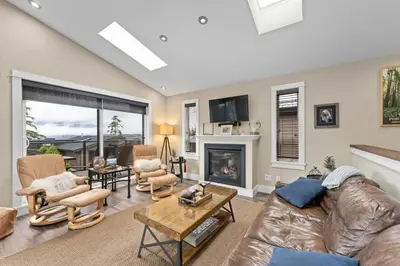 a living room with a leather couch and a fireplace at Spacious Oceanview - 2 living rooms & fridges - Pet Friendly in Port Renfrew