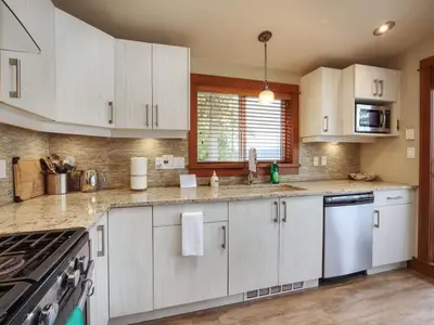 a kitchen with white cabinets and a stove top oven at Oceanfront view - Pet Friendly - Sleep 8 in Port Renfrew