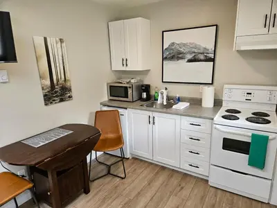 a kitchen with white cabinets and a sink and a stove at Cozy Rainforest Cottage for 2 - Pet Friendly in Port Renfrew