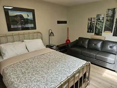a bedroom with a bed and a couch at Cozy Rainforest Cottage for 2 - Pet Friendly in Port Renfrew