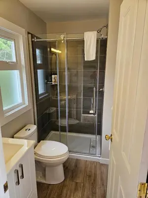 a bathroom with a toilet and a glass shower at Cozy Rainforest Cottage for 2 - Pet Friendly in Port Renfrew