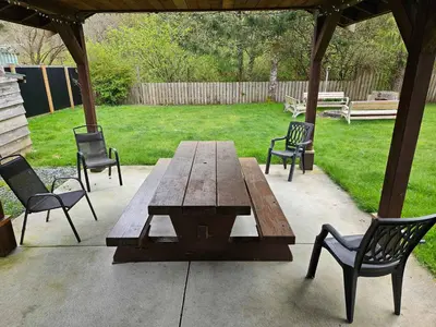 a wooden picnic table and chairs in a yard at The Outfitter - Garden View - Pet Friendly - Huge yard in Port Renfrew