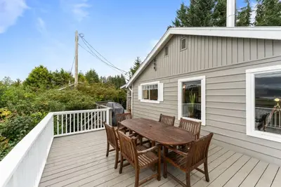 a wooden table and chairs on a deck at The Point Partial - Hot tub - Sauna - view of San Juan Bay - Pet Friendly in Port Renfrew