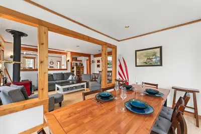 a dining room and living room with a wooden table at The Point Partial - Hot tub - Sauna - view of San Juan Bay - Pet Friendly in Port Renfrew