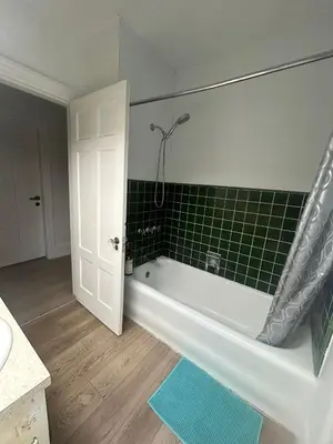 a bathroom with a tub and a green tile wall at Vancouver Budget Stay - Airport 10 Min - Free Parking & Fast WiFi in Vancouver