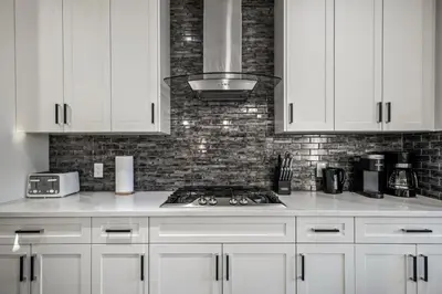 a kitchen with white cabinets and a stove top oven at Spacious 8 Bedroom Family Retreat in Calgary