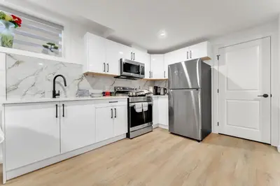a kitchen with white cabinets and a stainless steel refrigerator at 2-bedroom suite close to Amenities and Airport with on pad parking in Leduc